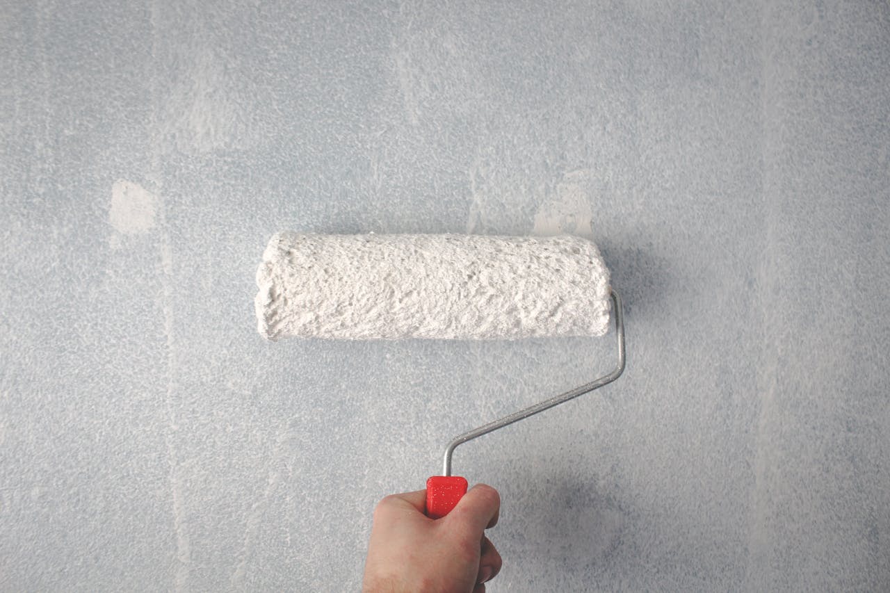 white paint with a big roller on a wall